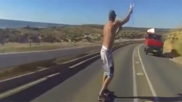 Neknomination auf dem Skateboard: Der Mann skatet auf einer befahreren Straße und trinkt dabei ein Bier aus einem Trichter