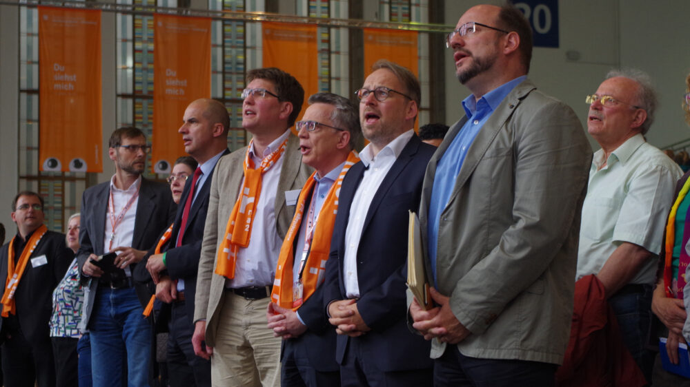 Der Bundesinnenminister Thomas de Maizière singt beim Christustag gemeinsam mit Uwe Heimowski, li. (Beauftragter der Deutschen Evangelischen Allianz am Sitz des Bundestags und der Bundesregierung) und Christoph Waffenschmidt, re. (Leiter World Vision Deutschland) aus voller Kehle