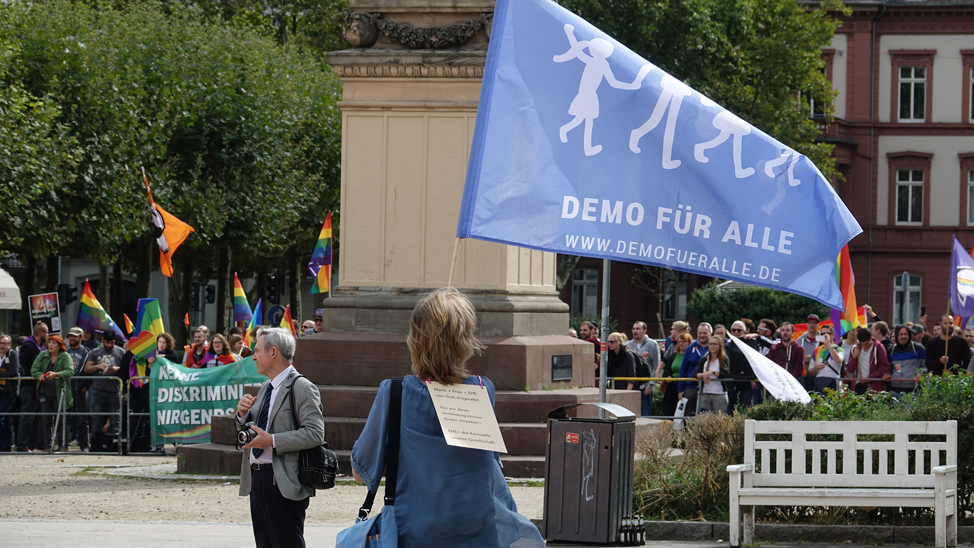 Eine Unterstützerin des „Busses der Meinungsfreiheit“ schwenkt anhaltend die „Demo für alle“-Fahne vor den Gegendemonstranten