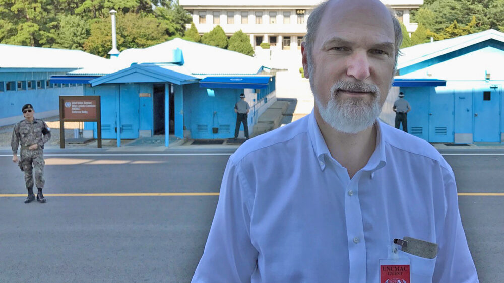 Thomas Schirrmacher vor der UN-Verhandlungsbaracke in der UN-Schutzzone in der Mitte der demilitarisierten Zone. Die Baracken stehen auf beiden Seiten der Grenze, das Gebäude im Hintergrund ist das Grenzhauptquartier der Nordkoreaner auf nordkoreanischem Boden.