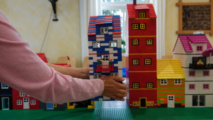 Eine Kinderhand setzt das selbstgebaute Haus in die Legostadt in der Christus-Gemeinde in Neukirchen-Vluyn