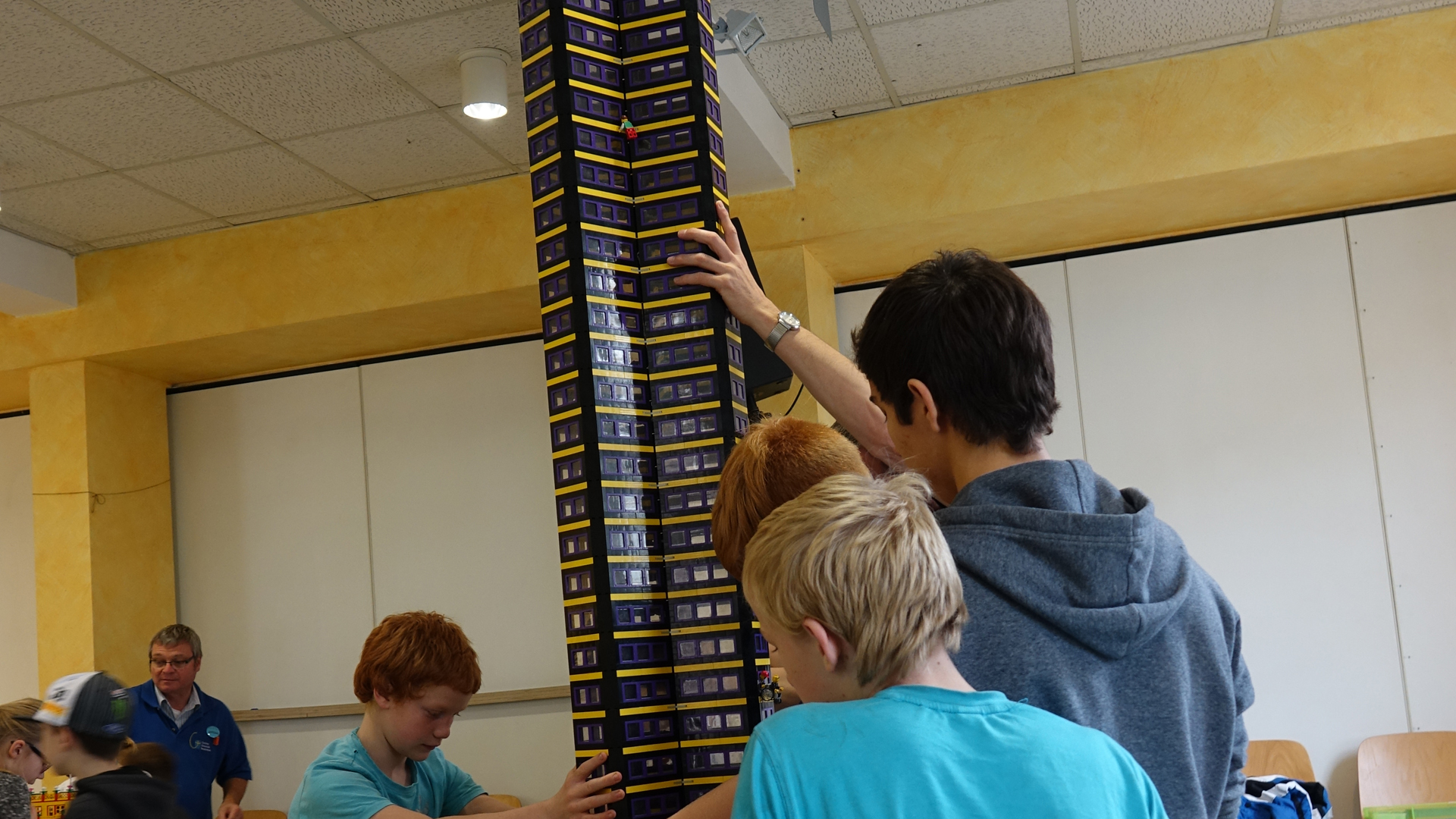 Mit vereinten Kräften heben die Kinder den wackeligen Turm auf die Bauplatte