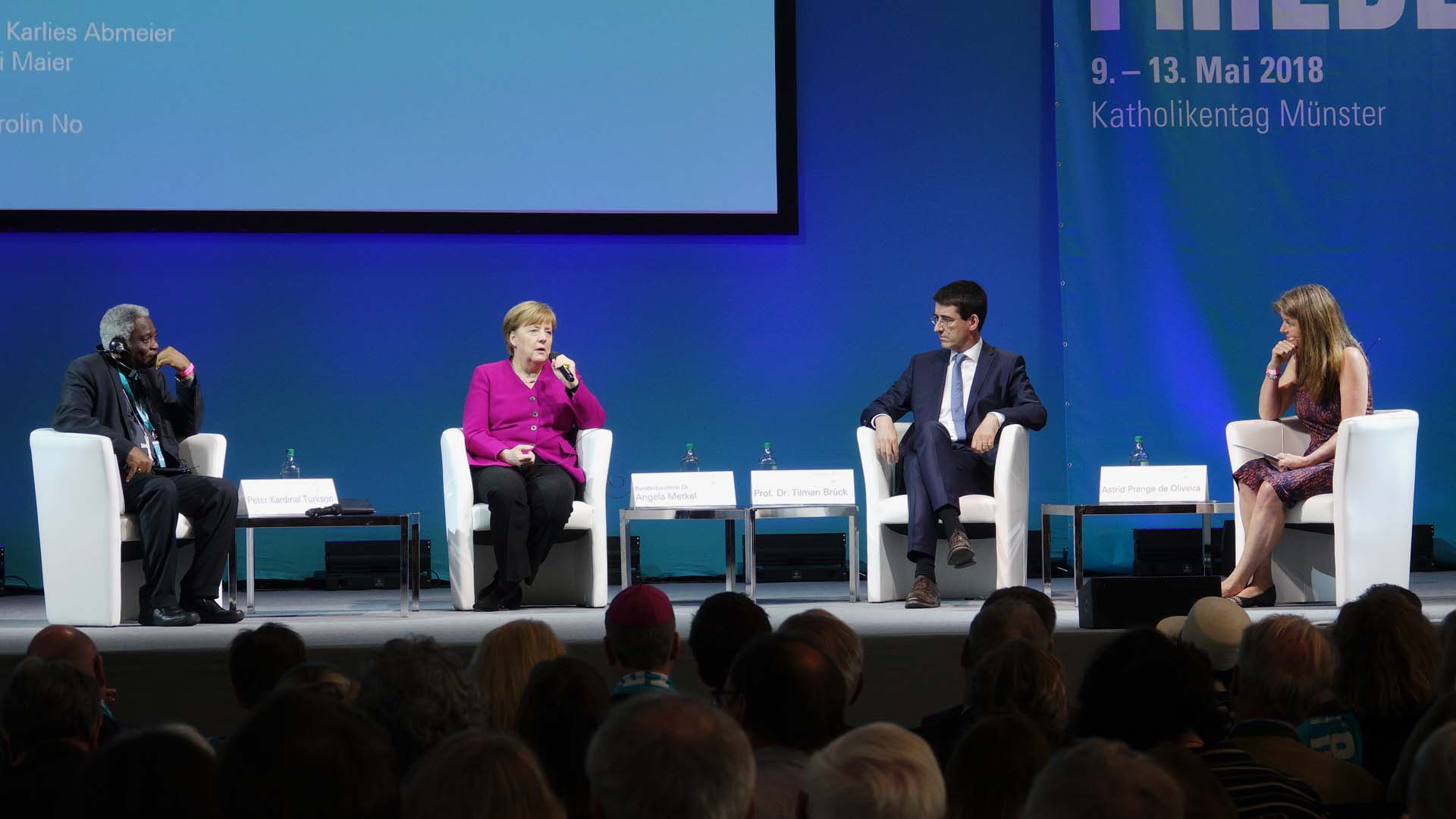 Peter Kardinal Turkson, Kanzlerin Angela Merkel und Professor Tilman Brück diskutieren auf dem Podium zum Thema „Deutschland in einer veränderten Weltlage – wie umgehen mit Konfliktherden und aggressiven Regimes?“ unter der Moderation von Astrid Prange de Oliveira (v.l.n.r.)