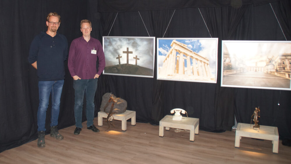 Tim Behrensmeier und Benjamin Carstens zeigen die Ausstellung. Rechts sind die drei Hügel (Golgatha, Akropolis und Kapitol in Rom) zu sehen, auf denen ein Staat gegründet sein sollte.