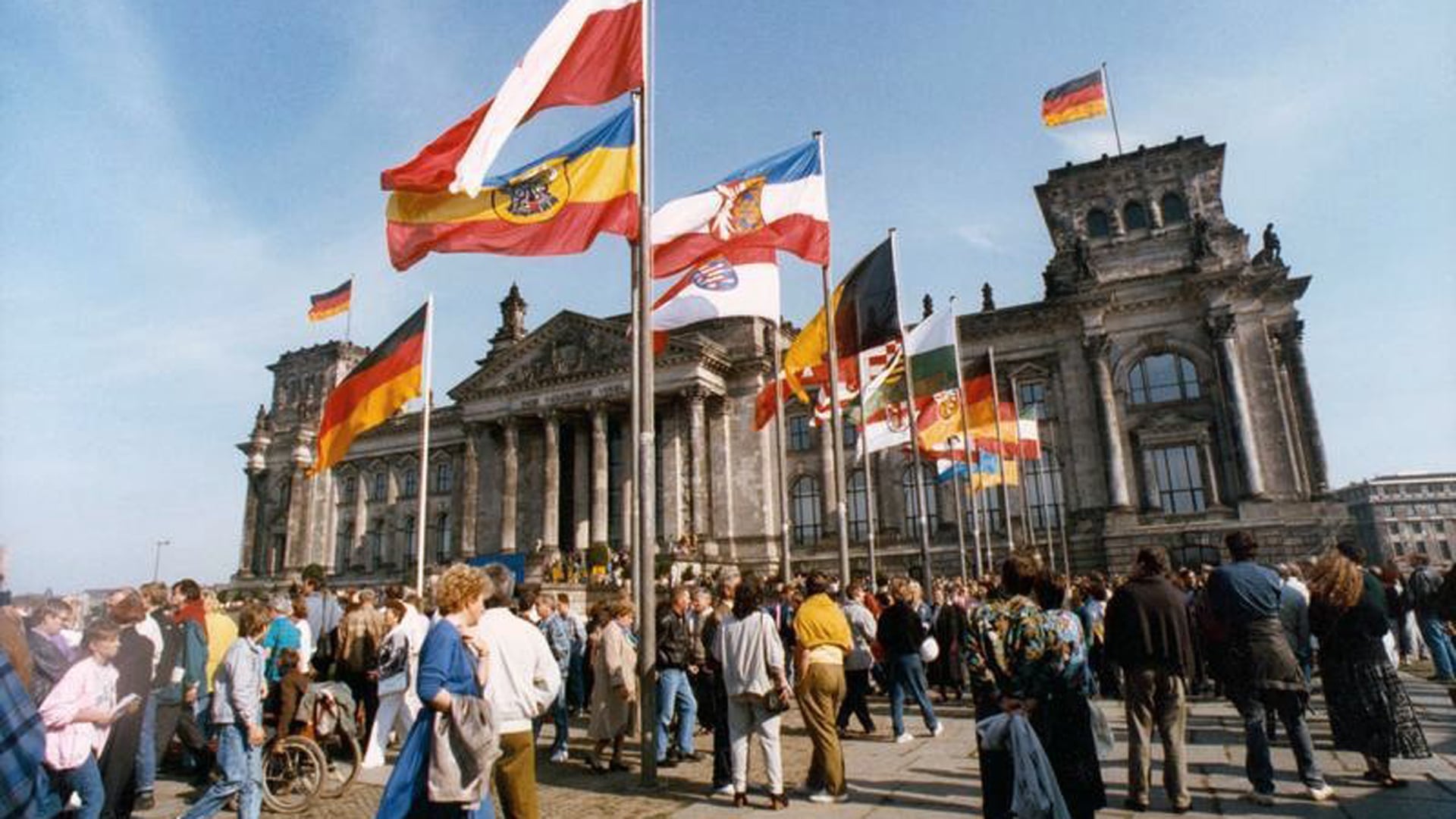 3. Oktober 1990: Um die schwarz-rot-goldene Fahne gruppieren sich vor dem Reichstagsgebäude in Berlin die Fahnen aller Bundesländer