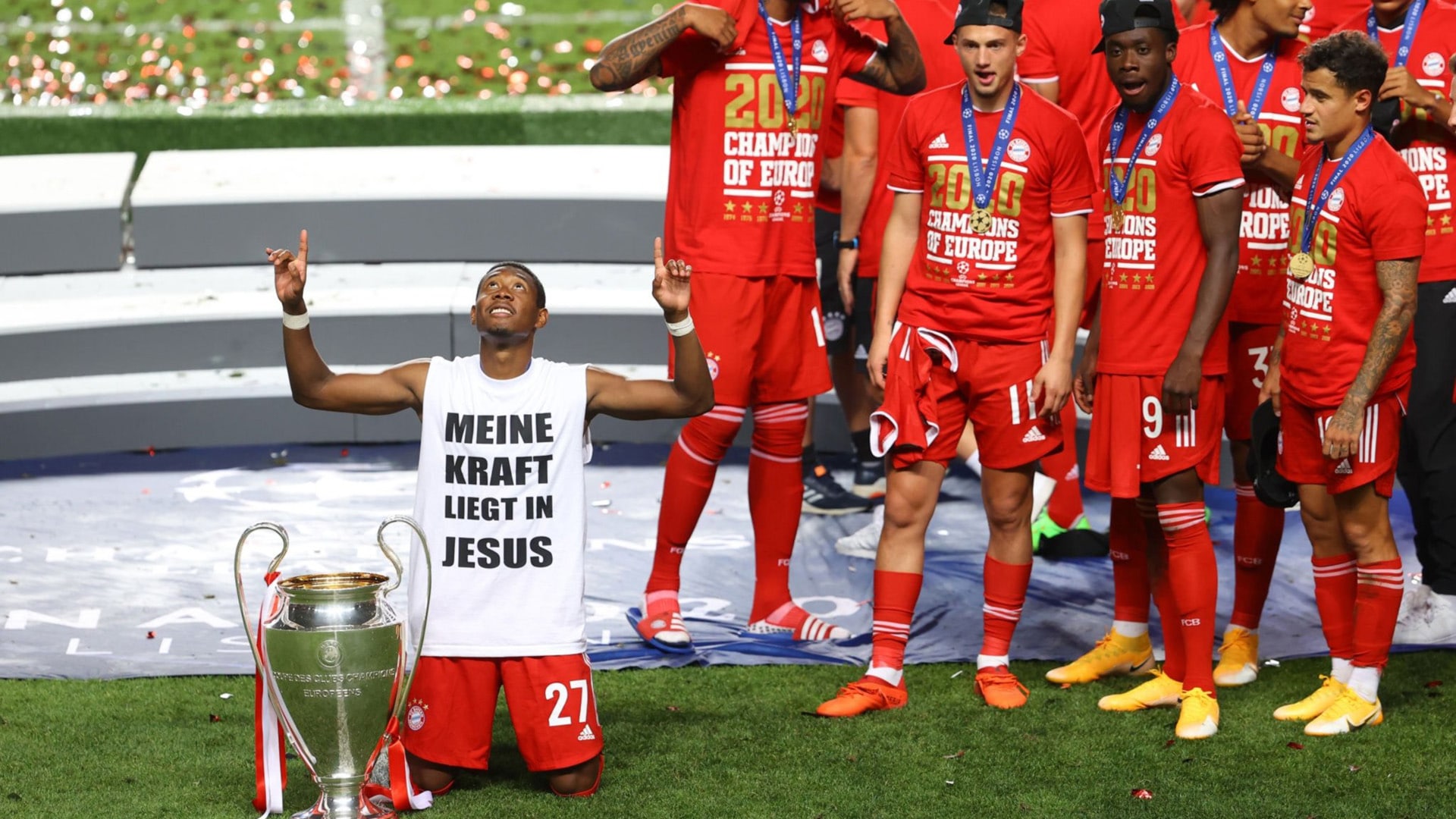 Bayern-Profi David Alaba kniet mit einem aussagekräftigen T-Shirt neben dem Champions-League-Pokal