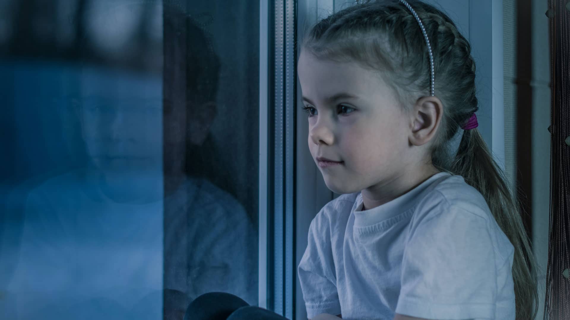 Trauriges Kind vor Fenster