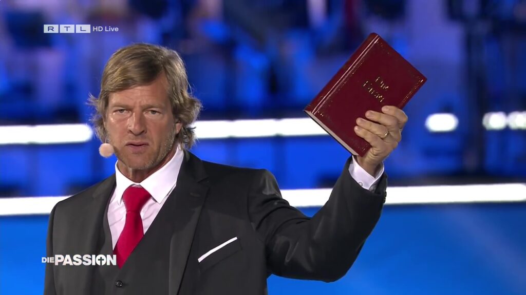 Henning Baum mit Bibel in der Hand bei „Die Passion“ von RTL