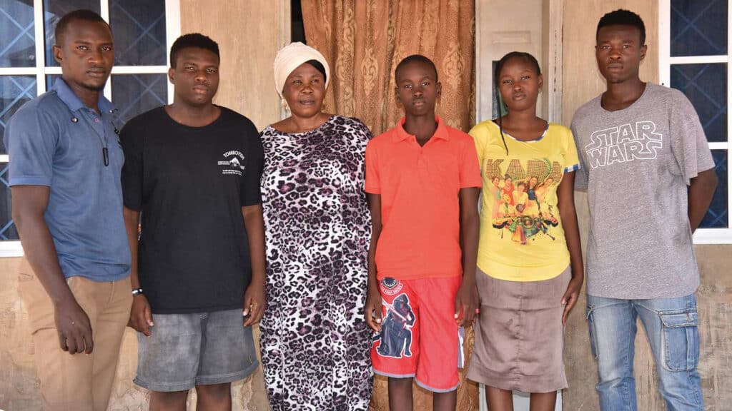 Junge Christen aus Nigeria stehen zusammen vor einem Haus