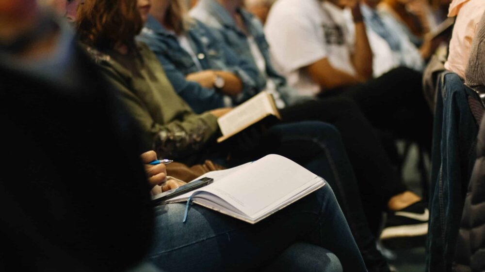 Menschen in einer Kirche mit Bibeln und Notizblöcken