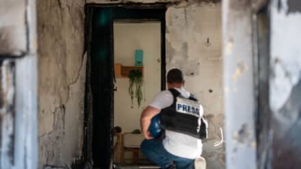 Journalist vor ausgebranntem Haus in Kfar Asa