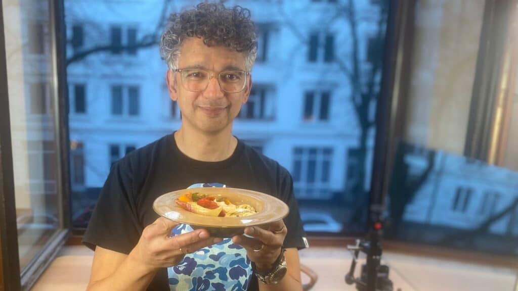 Bild vom kochenden Pastor mit einem Teller und das fertige Gericht an der Hand