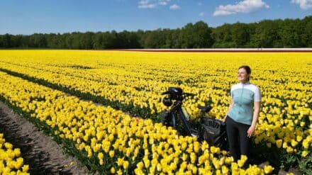 Carola Mehltretter auf einem Feld voller Blüten mit ihrem E-Bike