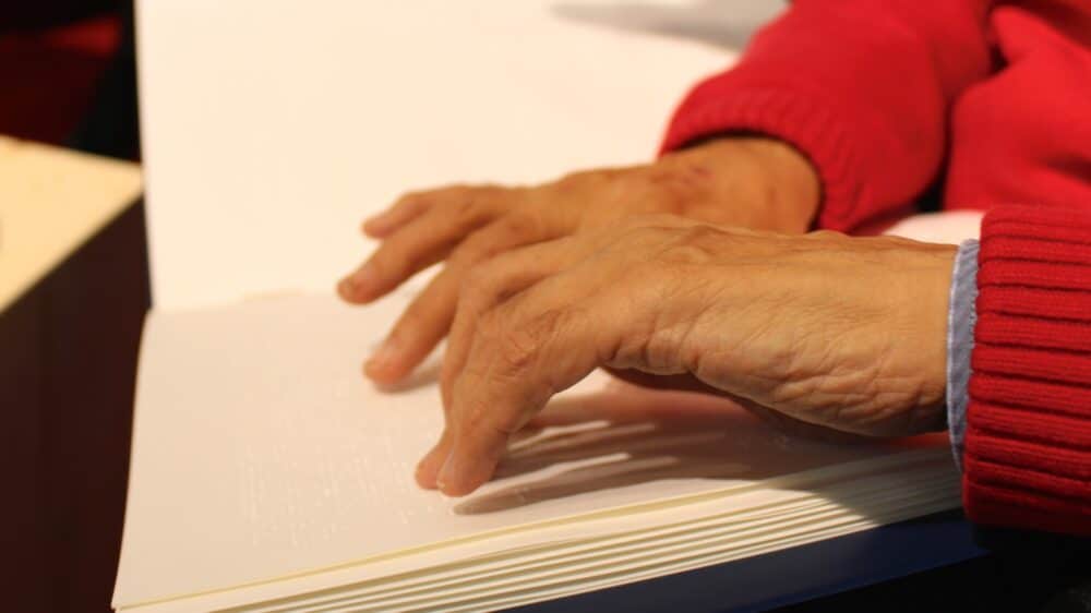 Braille-Bibel, Hand von einer Person, die diese Bibel mit den Händen liest