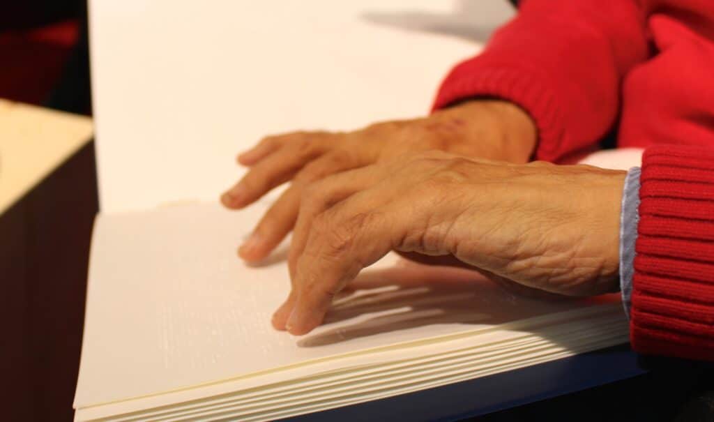 Braille-Bibel, Hand von einer Person, die diese Bibel mit den Händen liest