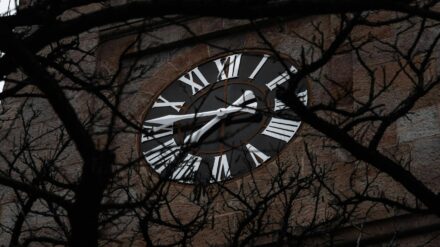 Uhr an einem Kirchturm mit Bäumen davor