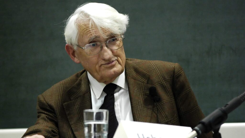 Jürgen Habermas sitzt an einem Tisch, vor ihm ein Mikrofon und ein Wasserglas