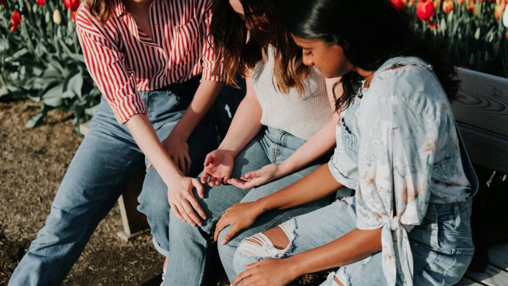 Frauen sitzen auf einer Bank und beten zusammen