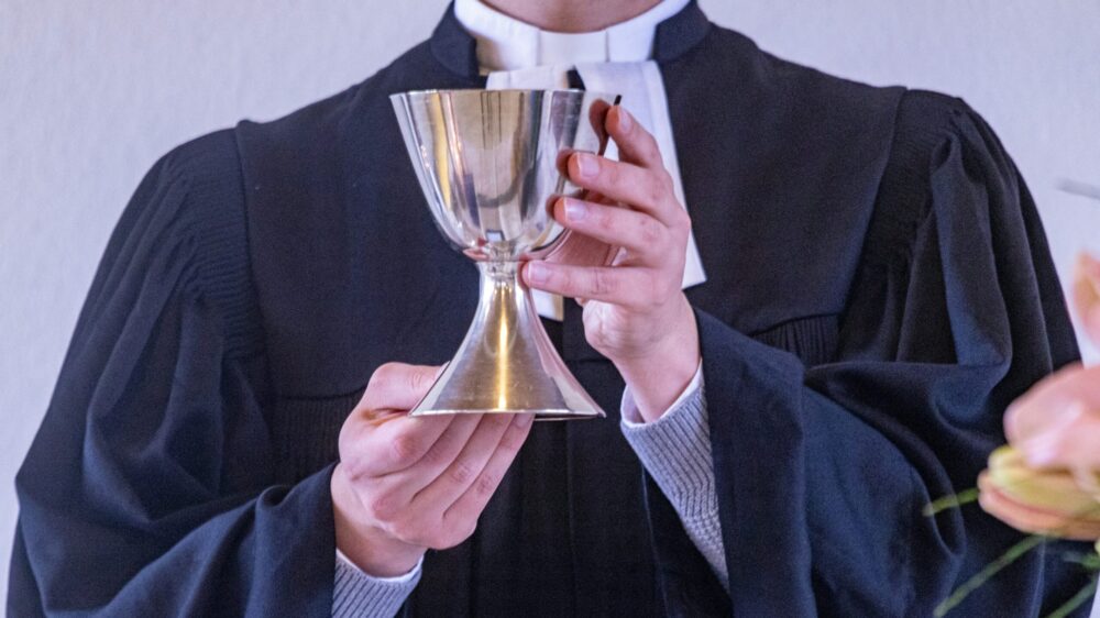 Ein evangelischer Pastor hält einen Abendmahlskelch